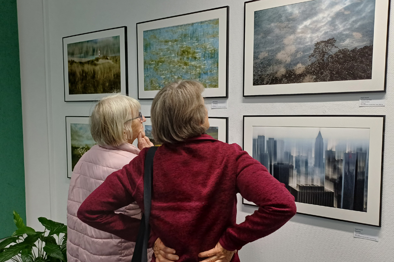 zwei Frauen betrachten Fotos an der Wand